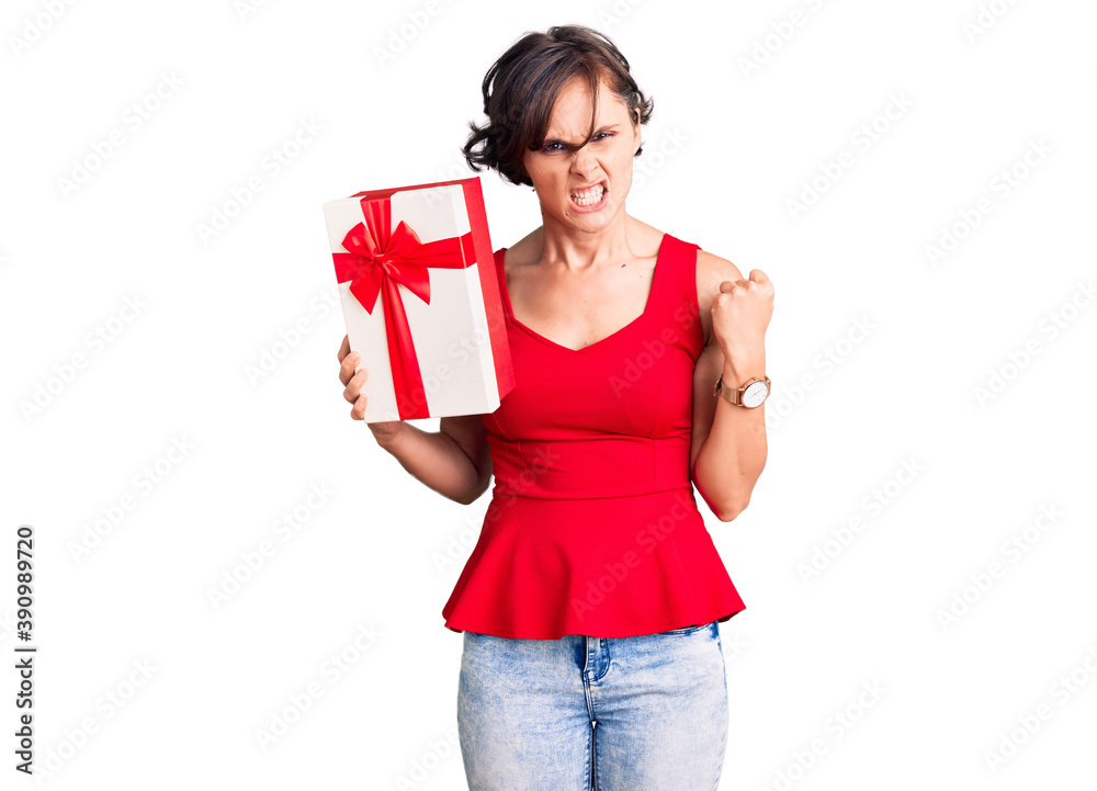 Beautiful young woman with short hair holding gift annoyed and frustrated shouting with anger, yelling crazy with anger and hand raised Beautiful young woman with short hair holding gift annoyed and frustrated shouting with anger, yelling crazy with anger and hand raised