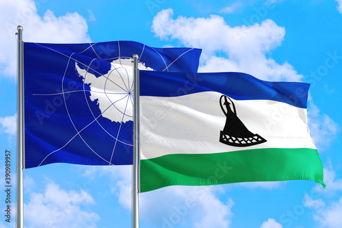 Lesotho and Antarctica national flag waving in the windy deep blue sky. Diplomacy and international relations concept.