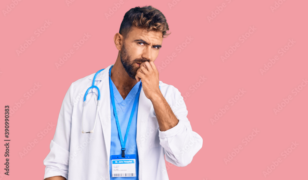 Young hispanic man wearing doctor uniform and stethoscope looking stressed and nervous with hands on mouth biting nails. anxiety problem. Young hispanic man wearing doctor uniform and stethoscope looking stressed and nervous with hands on mouth biting nails. anxiety problem.