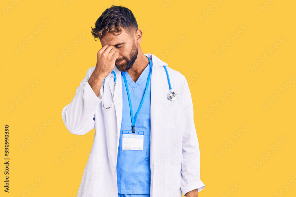 Young hispanic man wearing doctor uniform and stethoscope tired rubbing nose and eyes feeling fatigue and headache. stress and frustration concept. Young hispanic man wearing doctor uniform and stethoscope tired rubbing nose and eyes feeling fatigue and headache. stress and frustration concept.