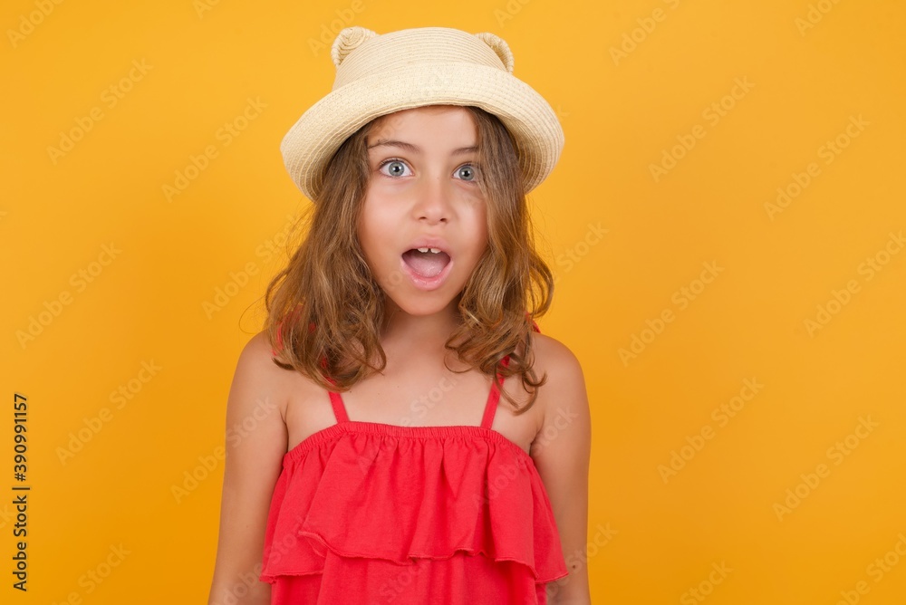 young Caucasian girl standing against yellow background having stunned and shocked look, with mouth open and jaw dropped exclaiming: Wow, I can't believe this. Surprise and shock