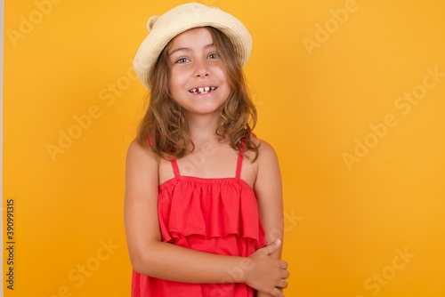 young Caucasian girl standing against yellow background laughing. © Jihan