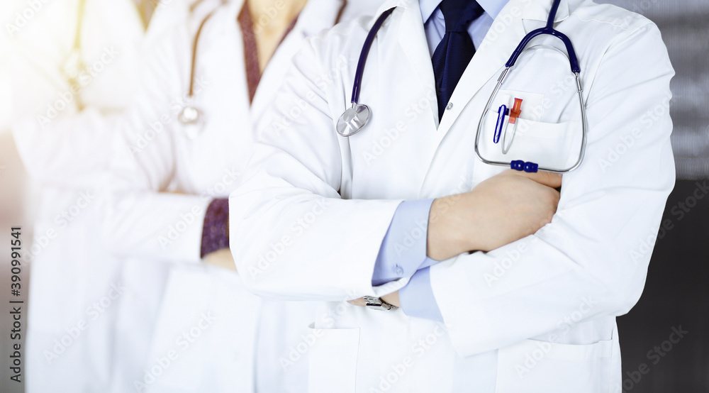 Group of modern doctors standing as a team with crossed arms and stethoscopes in a sunny hospital office. Physicians ready to examine and help patients. Medical help, insurance in health care, best Group of modern doctors standing as a team with crossed arms and stethoscopes in a sunny hospital office. Physicians ready to examine and help patients. Medical help, insurance in health care, best