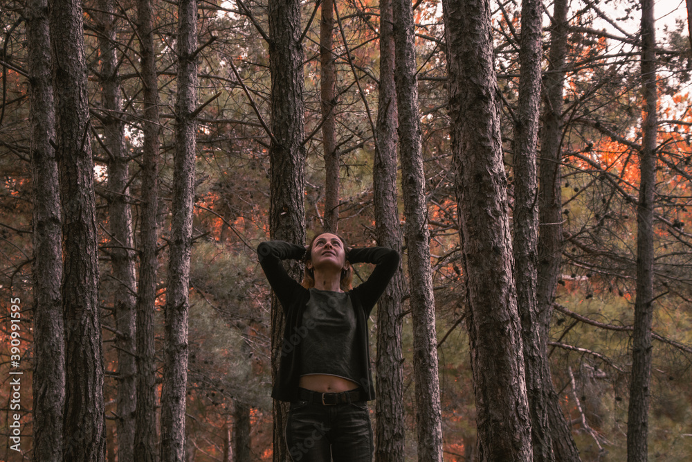 The beautiful and young woman is looking at the sky and touching her hair in the autumn forest The beautiful and young woman is looking at the sky and touching her hair in the autumn forest