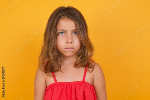 young Caucasian girl standing against yellow background blinking eyes with pleasure having happy expression. Facial expressions and people emotions concept.