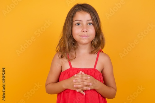 Business Concept - Portrait of Caucasian young girl standing against yellow background holding hands with confident face.