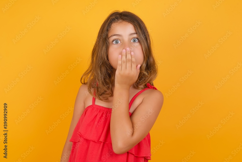 Oh! I think I said it! Close up portrait Caucasian young girl standing against yellow background cover open mouth by hand palm, look at camera with big eyes. Oh! I think I said it! Close up portrait Caucasian young girl standing against yellow background cover open mouth by hand palm, look at camera with big eyes.