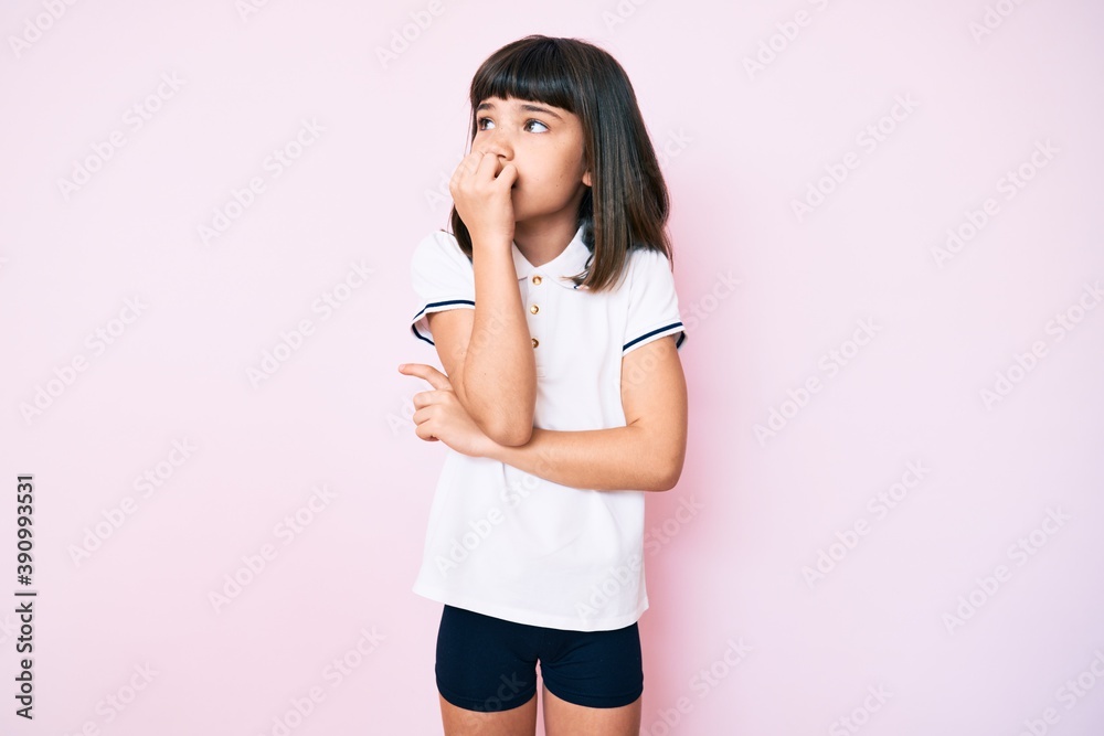 Young little girl with bang wearing sportswear looking stressed and nervous with hands on mouth biting nails. anxiety problem. Young little girl with bang wearing sportswear looking stressed and nervous with hands on mouth biting nails. anxiety problem.