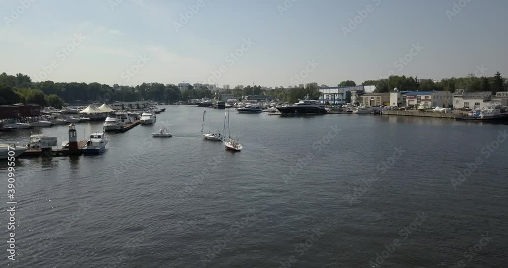 4K high quality calm windless bright summer morning aerial video of Moscow Channel yacht club embankment, green trees, wooden pier and shore with moored anchored boats and yachts near Moscow, Russia