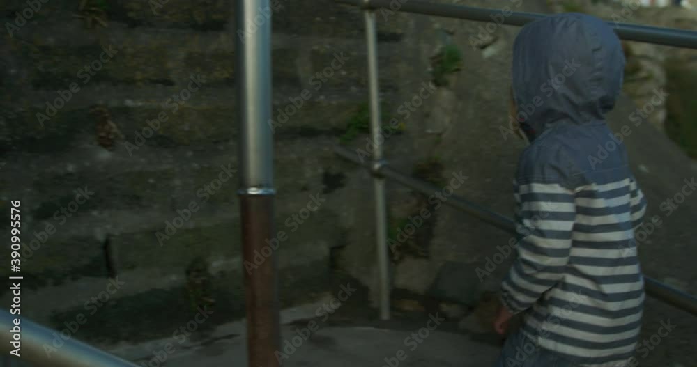 A little preschooler is walking up some steps by the coast in autumn A little preschooler is walking up some steps by the coast in autumn