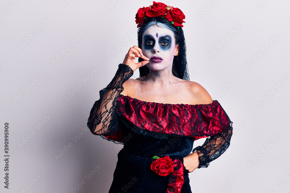Young woman wearing mexican day of the dead makeup mouth and lips shut as zip with fingers. secret and silent, taboo talking Young woman wearing mexican day of the dead makeup mouth and lips shut as zip with fingers. secret and silent, taboo talking