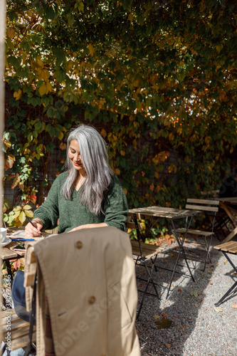Mature pale hair stylish woman lifestyle portrait outdoors near cafe