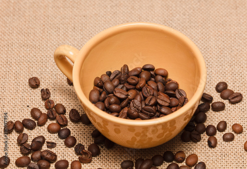
yellow coffee cup with grains and raffia cloth background
