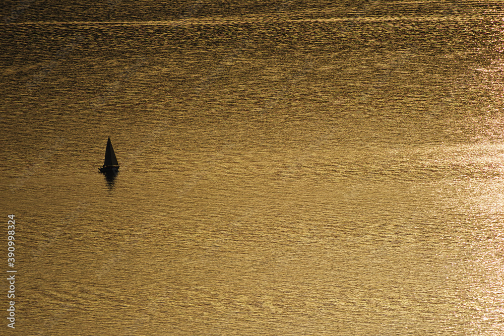 Einsames Segelboot bei ruhigem Wasser während des Sonnenuntergangs