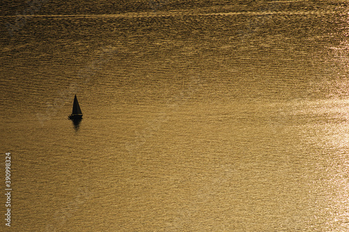 Obraz na płótnie Einsames Segelboot bei ruhigem Wasser während des Sonnenuntergangs w salonie