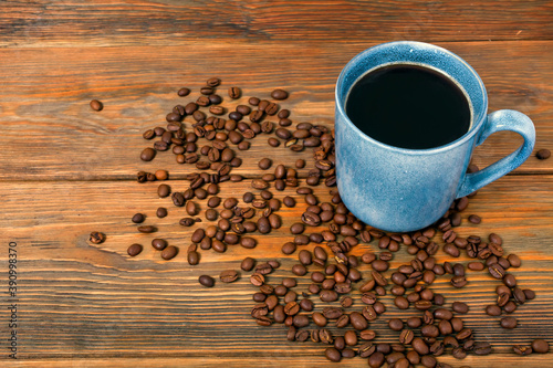 Cup of black coffee with roasted coffee beans on a wooden background.