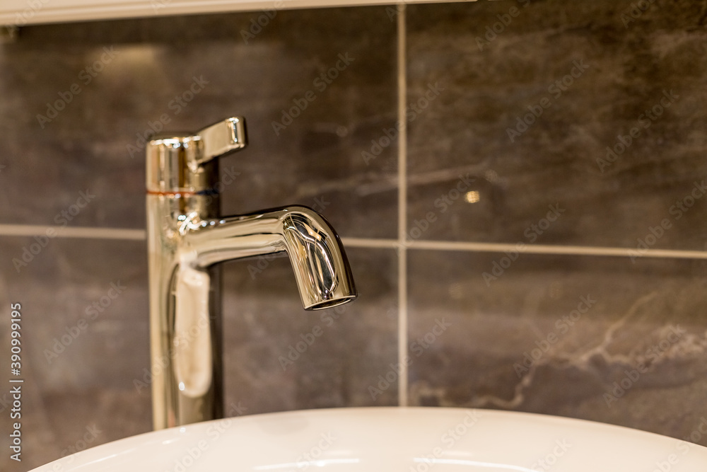 Chrome water faucet with marble counter tops and a white sink.Luxury faucet mixer in a beautiful gray bathroom. Sanitary prevention antivirus concept.Selective focus