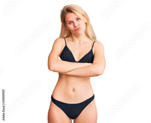 Young beautiful blonde woman wearing bikini skeptic and nervous, disapproving expression on face with crossed arms. negative person.