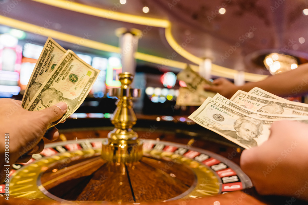 Φωτογραφία hand hold money bill bet at roulette wheel at casino club gambling game ideas co