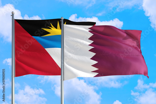 Qatar and Antigua and Barbuda national flag waving in the windy deep blue sky. Diplomacy and international relations concept.