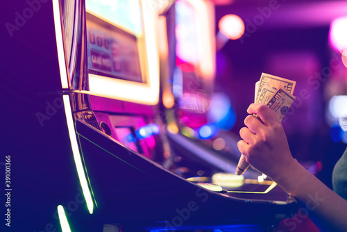 Slot Machine Play Time. Female Gambler Hand hold money bill ready to win the game with one best shot casino close up