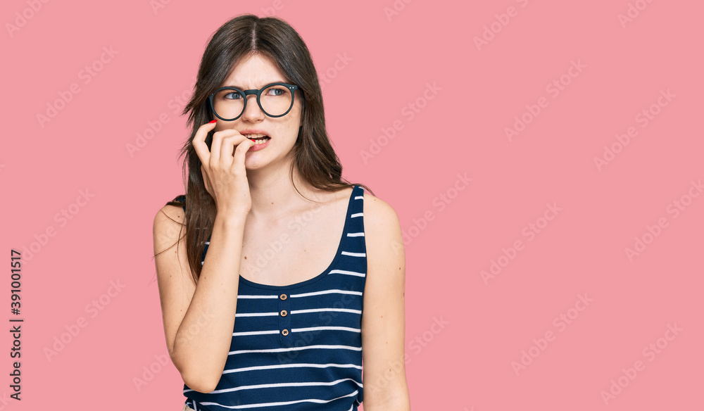 Young beautiful caucasian girl wearing casual clothes and glasses looking stressed and nervous with hands on mouth biting nails. anxiety problem. Young beautiful caucasian girl wearing casual clothes and glasses looking stressed and nervous with hands on mouth biting nails. anxiety problem.