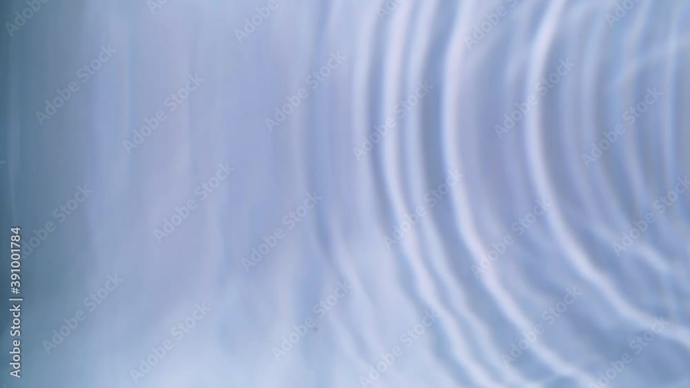Top view slow motion of drop falling into the water surface and diverging circles on white background Top view slow motion of drop falling into the water surface and diverging circles on white background