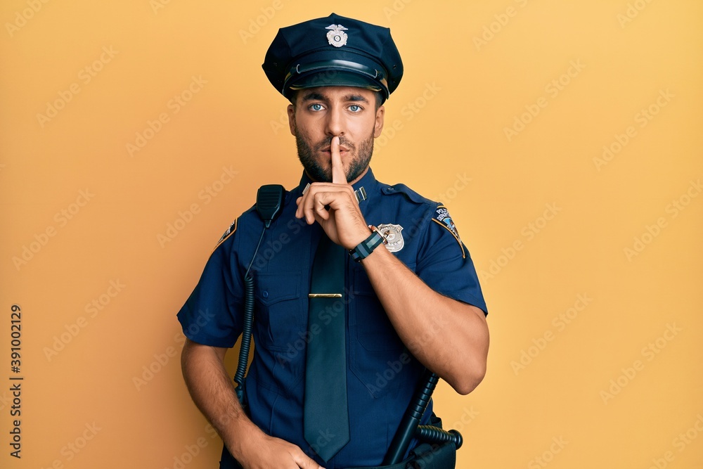 Handsome hispanic man wearing police uniform asking to be quiet with finger on lips. silence and secret concept. Handsome hispanic man wearing police uniform asking to be quiet with finger on lips. silence and secret concept.