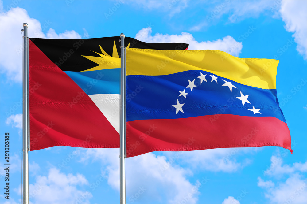 Fototapeta premium Venezuela and Antigua and Barbuda national flag waving in the windy deep blue sky. Diplomacy and international relations concept.