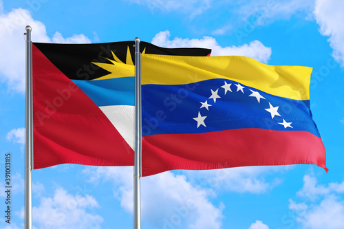 Venezuela and Antigua and Barbuda national flag waving in the windy deep blue sky. Diplomacy and international relations concept.