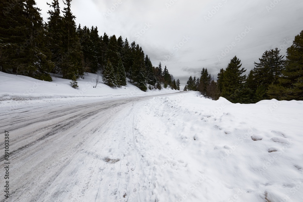 Obraz premium Snowy mountain road streching through the hills