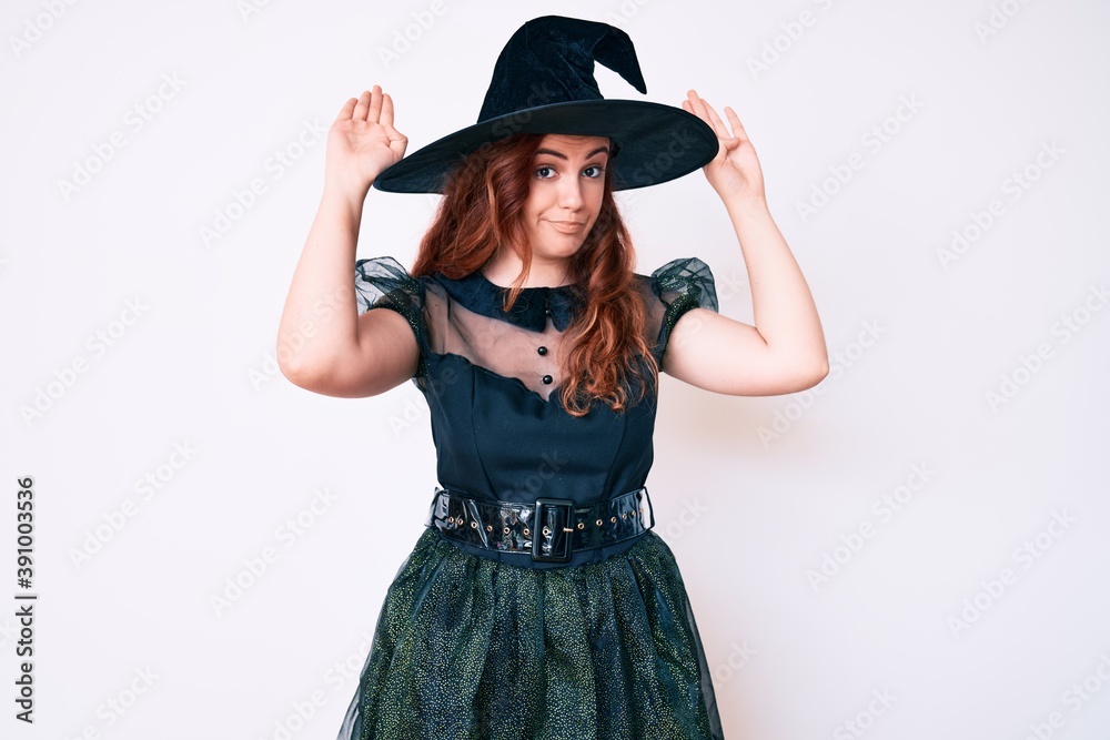 Young beautiful woman wearing witch halloween costume doing bunny ears gesture with hands palms looking cynical and skeptical. easter rabbit concept. Young beautiful woman wearing witch halloween costume doing bunny ears gesture with hands palms looking cynical and skeptical. easter rabbit concept.