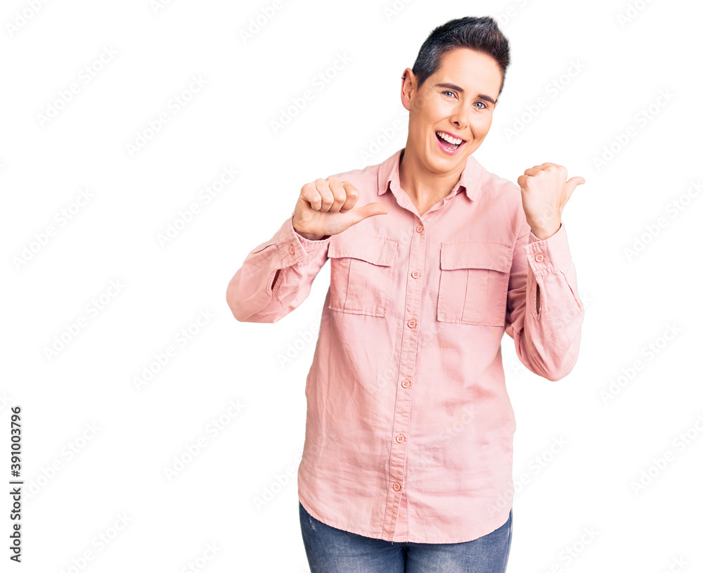 Young woman with short hair wearing casual clothes pointing to the back behind with hand and thumbs up, smiling confident Young woman with short hair wearing casual clothes pointing to the back behind with hand and thumbs up, smiling confident