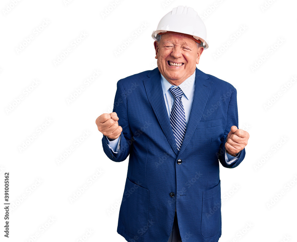 Senior handsome grey-haired man wearing suit and architect hardhat very happy and excited doing winner gesture with arms raised, smiling and screaming for success. celebration concept. Senior handsome grey-haired man wearing suit and architect hardhat very happy and excited doing winner gesture with arms raised, smiling and screaming for success. celebration concept.