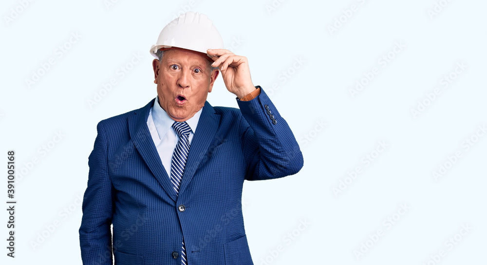 Senior handsome grey-haired man wearing suit and architect hardhat surprised with hand on head for mistake, remember error. forgot, bad memory concept.