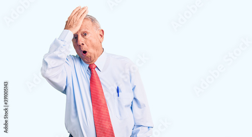 Senior handsome grey-haired man wearing elegant tie and shirt surprised with hand on head for mistake, remember error. forgot, bad memory concept.