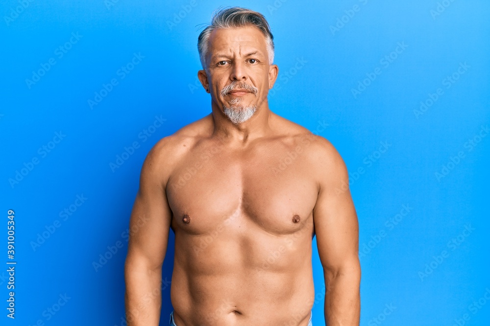 Middle age grey-haired man standing shirtless relaxed with serious expression on face. simple and natural looking at the camera. Middle age grey-haired man standing shirtless relaxed with serious expression on face. simple and natural looking at the camera.