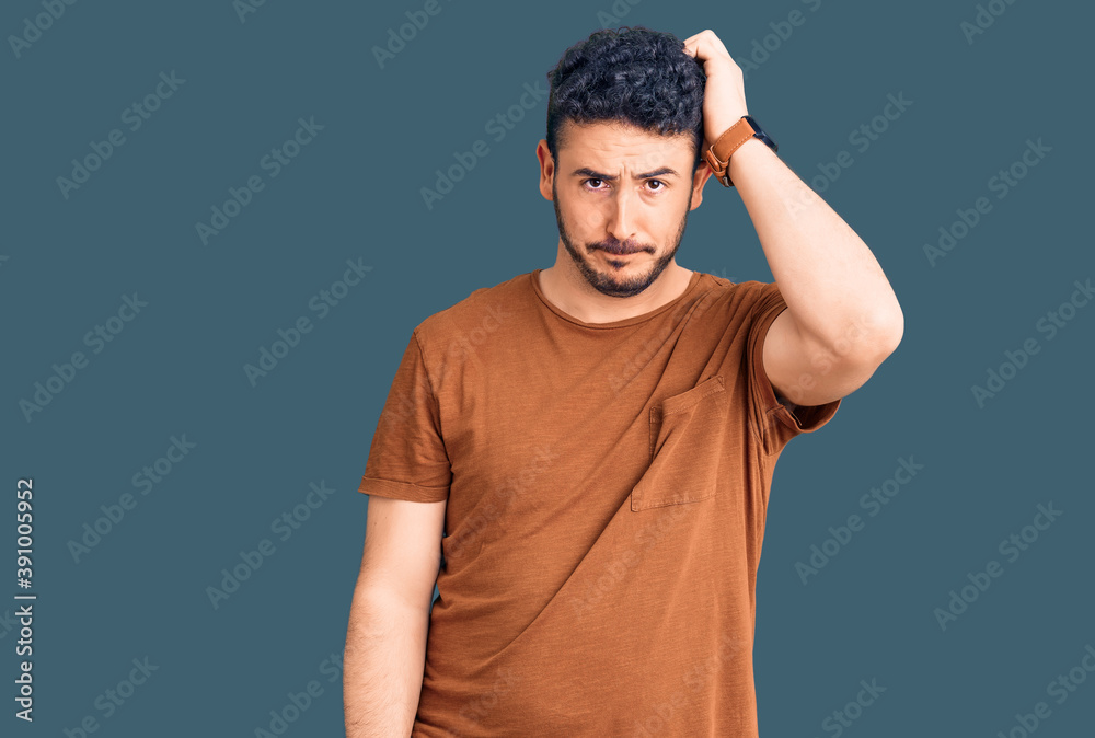 Young hispanic man wearing casual clothes confuse and wonder about question. uncertain with doubt, thinking with hand on head. pensive concept.