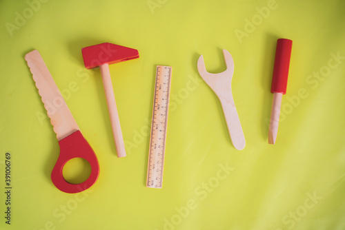Toy tools on a green background. Hammer, ruler, wrench, screwdriver, saw. Working equipment
