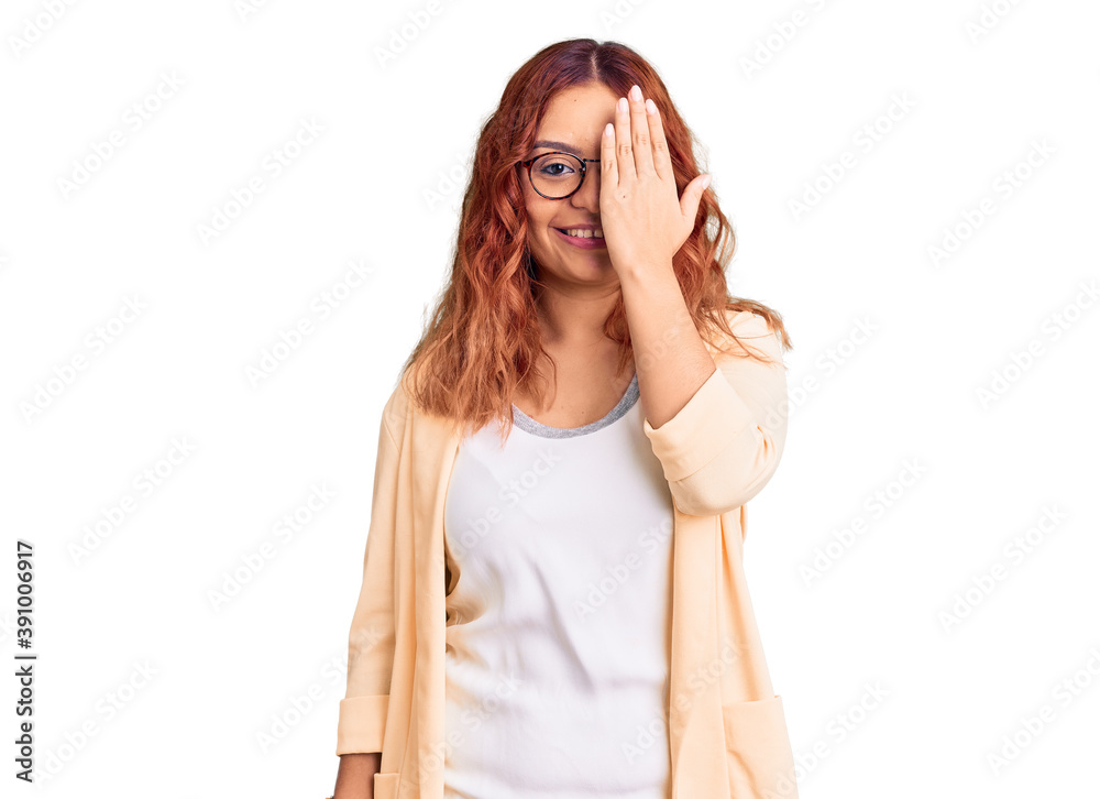 Young latin woman wearing business clothes covering one eye with hand, confident smile on face and surprise emotion. Young latin woman wearing business clothes covering one eye with hand, confident smile on face and surprise emotion.