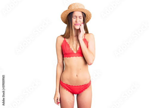 Beautiful brunette young woman wearing bikini touching mouth with hand with painful expression because of toothache or dental illness on teeth. dentist