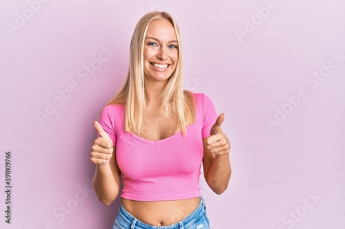 Young blonde girl wearing casual clothes success sign doing positive gesture with hand, thumbs up smiling and happy. cheerful expression and winner gesture. © Krakenimages.com