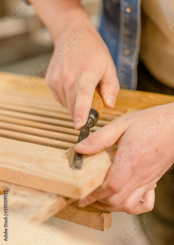Close up hands of carpenter with chisel in the hands on the workbench in carpentry