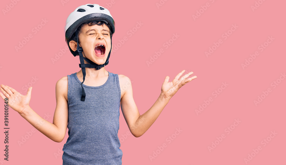 Little cute boy kid wearing bike helmet celebrating mad and crazy for success with arms raised and closed eyes screaming excited. winner concept Little cute boy kid wearing bike helmet celebrating mad and crazy for success with arms raised and closed eyes screaming excited. winner concept