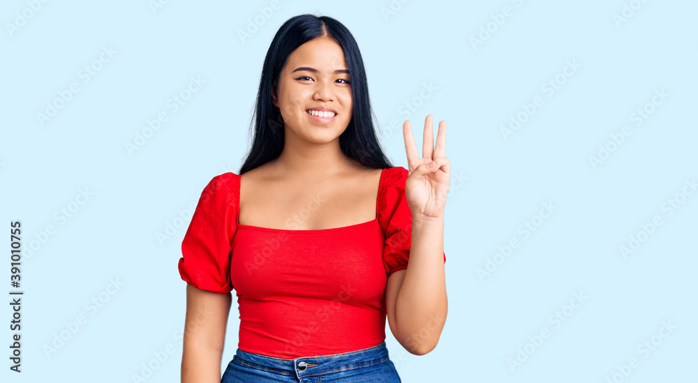 Young beautiful asian girl wearing casual clothes showing and pointing up with fingers number three while smiling confident and happy. Young beautiful asian girl wearing casual clothes showing and pointing up with fingers number three while smiling confident and happy.