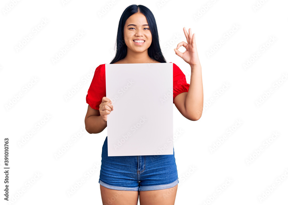 Young beautiful asian girl holding blank empty banner doing ok sign with fingers, smiling friendly gesturing excellent symbol Young beautiful asian girl holding blank empty banner doing ok sign with fingers, smiling friendly gesturing excellent symbol