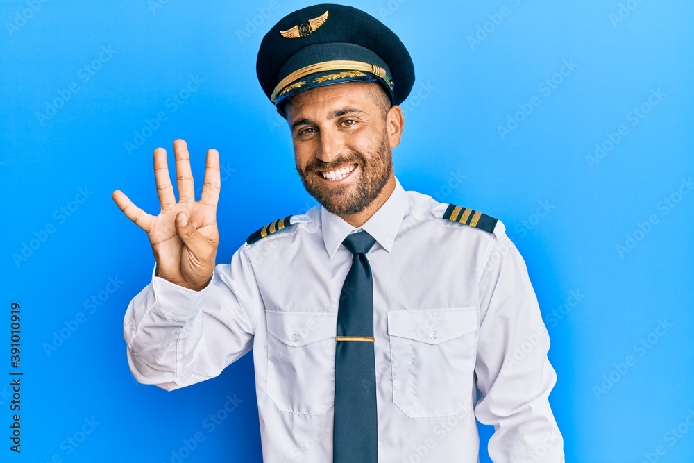 Handsome man with beard wearing airplane pilot uniform showing and pointing up with fingers number four while smiling confident and happy. Handsome man with beard wearing airplane pilot uniform showing and pointing up with fingers number four while smiling confident and happy.