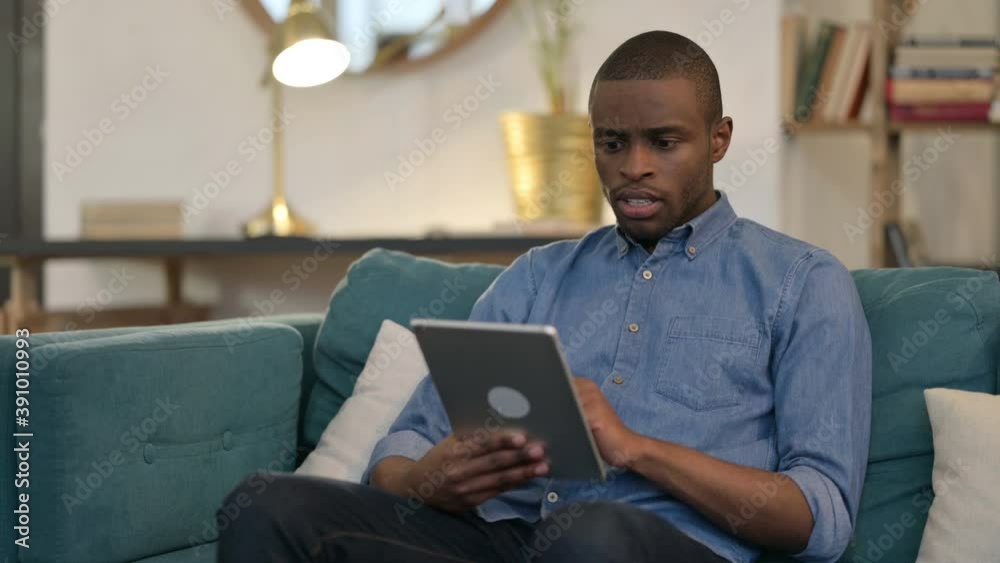 Success, Young African Man Celebrating On Tablet on Sofa Success, Young African Man Celebrating On Tablet on Sofa