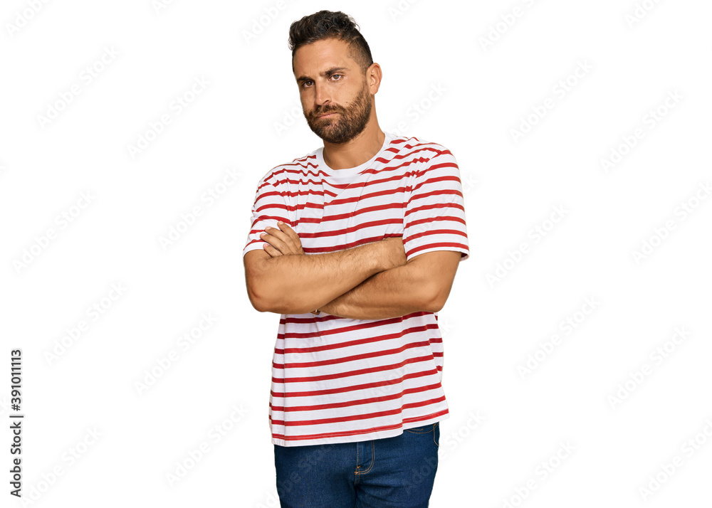 Handsome man with beard wearing striped tshirt skeptic and nervous, disapproving expression on face with crossed arms. negative person. Handsome man with beard wearing striped tshirt skeptic and nervous, disapproving expression on face with crossed arms. negative person.