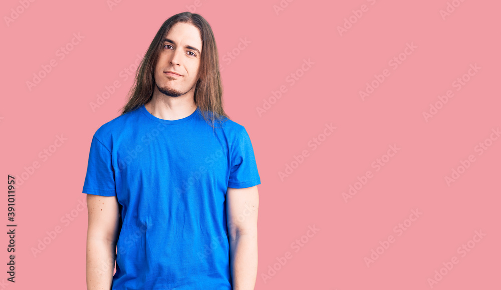 Obraz premium Young adult man with long hair wearing swimwear relaxed with serious expression on face. simple and natural looking at the camera.